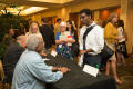Photograph: [Attendee standing at signing table]