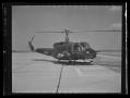 Photograph: [Photograph of a YUH-1D Iroquois helicopter parked on a concrete surf…