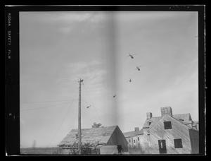 Primary view of object titled '[Photograph of five UH-1B Iroquois helicopters flying over a war-zone simulation area]'.