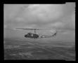 Photograph: [Photograph of a UH-1L Iroquois helicopter flying over a city]