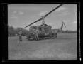 Primary view of [Photograph of two soldiers standing by a UH-1B Iroquois helicopter in a field]