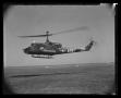 Photograph: [Photograph of a UH-1B Iroquois helicopter hovering over a field]