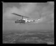 Primary view of [Photograph of a UH-1L Iroquois helicopter flying over a city, 2]