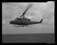 Photograph: [Photograph of a UH-1B Iroquois helicopter flying above a field]