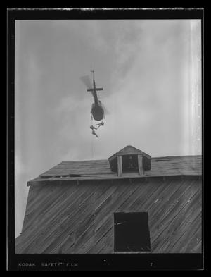 Primary view of object titled '[Photograph of three soldiers rappelling out of a UH-1B Iroquois helicopter]'.
