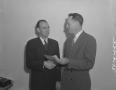 Photograph: [Two Men Shaking Hands and Holding a Paper Slip]