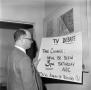 Photograph: [Dr. William Robert DeMougeot looking at a poster #1]