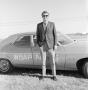 Photograph: [Budd standing in front of a WBAP car]