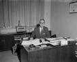 Primary view of [Roy Newman seated at desk]