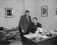 Photograph: [Two men posing at a desk at WBAP]