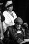 Photograph: [Photograph of a woman standing up behind Melvin Van Peebles on stage]