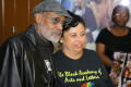 Photograph: [Photograph of Melvin Van Peebles with a woman wearing a TBAAL shirt,…