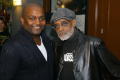 Photograph: [Photograph of Melvin Van Peebles posing with a man in a black sweate…