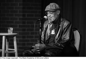 Primary view of object titled '[Photograph of Melvin Van Peebles sitting in front of a microphone]'.