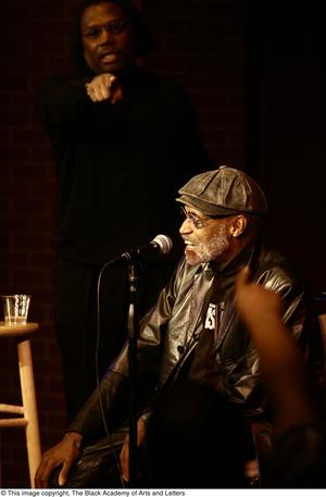 Primary view of object titled '[Photograph of Melvin Van Peebles on a stage with an unidentified man]'.