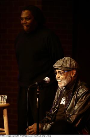 Primary view of object titled '[Photograph of Melvin Van Peebles and an unidentified man on a stage]'.