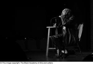 Primary view of object titled '[Photograph of Melvin Van Peebles sitting with a microphone]'.