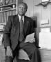 Photograph: [Dr. Norman E. Dyer leaning against his desk and holding a report #4]