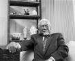 Photograph: [Dr. Donald A. Brooks seated in his living room]