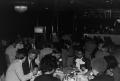 Photograph: [Photograph of various individuals sitting at different dining tables]