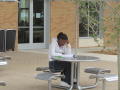 Photograph: [Student at table outside of Business Leadership Building]