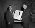 Photograph: [Roy Bacus holding a drawing with Doc Rhuman]
