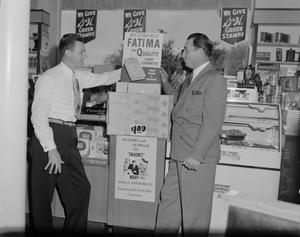 Primary view of object titled '[Men standing next to a cigarette display]'.