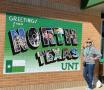 Photograph: [Alumna with "Greetings from North Texas" Mural]