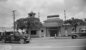 Primary view of object titled '[Photograph of a taxi driving by a restaurant]'.