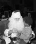 Primary view of [Photograph of Santa holding a little boy at a KXAS Christmas Children's Hour party]