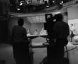 Photograph: [Camera operators silhouette filming news team]