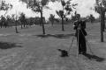 Photograph: [Photograph of Byrd Williams III setting up a tripod outdoors, 3]