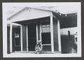 Photograph: [Photograph of a man sitting on a porch and holding a baby]