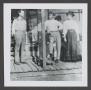 Photograph: [Photograph of two men and a woman standing on a porch]