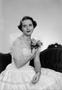Photograph: [Woman in a dress, holding a floral garter]