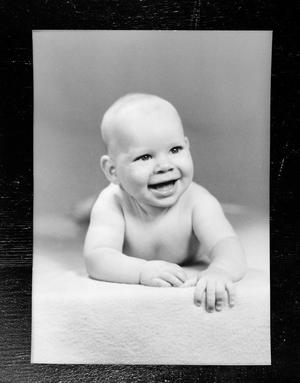 Primary view of object titled '[Baby laying on the floor, smiling]'.