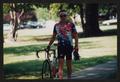 Primary view of [Cyclist Chuck Taylor walking with his bike: Lone Star Ride 2002 event photo]