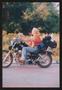 Primary view of [Woman ridding by on her motorcycle with camping gear: Lone Star Ride 2004 event photo]