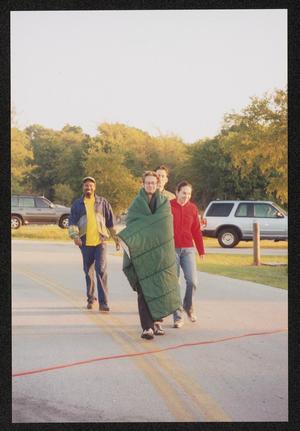 Primary view of object titled '[Four individuals walking in from a parking lot: Lone Star Ride 2001 event photo]'.