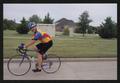 Photograph: [A cyclists smiles wide as he rides through a neighborhood: Lone Star…
