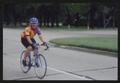 Thumbnail image of item number 1 in: '[A cyclist on a blue bike rides down a wide street: Lone Star Ride event photo]'.