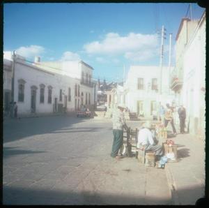 Primary view of object titled '[People standing and sitting at a sidewalk]'.