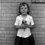 Photograph: [A child standing in front of a brick wall]