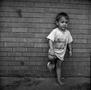 Primary view of [Photograph of a boy standing in front of a brick wall #1]
