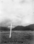 Photograph: [A cross in a field with mountains in the background]