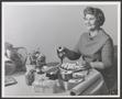 Photograph: [Julia Dell Hunter seated at a table of food]