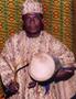 Photograph: [Gideon Alorwoyie dressed in patterned white clothing and holding a d…