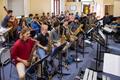 Thumbnail image of item number 1 in: '[Rows of woodwind and brass musicians performing in a room, 1]'.