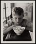 Photograph: [A boy looking down at a bowl, 1]