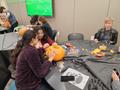 Photograph: [Students carving on spare pumpkin, 2]